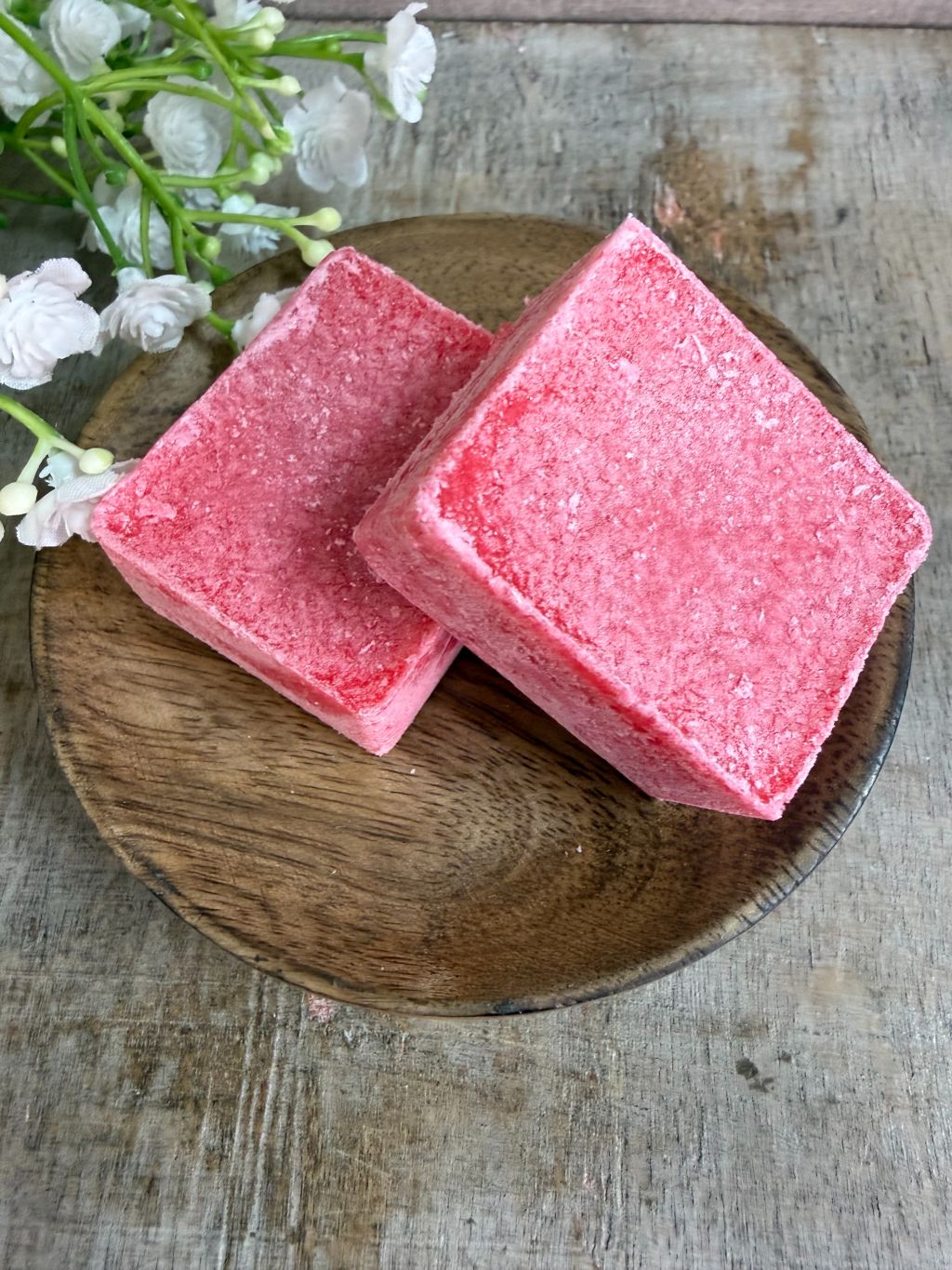 Roze amberblokjes met een frisse katoengeur op een houten schaaltje.