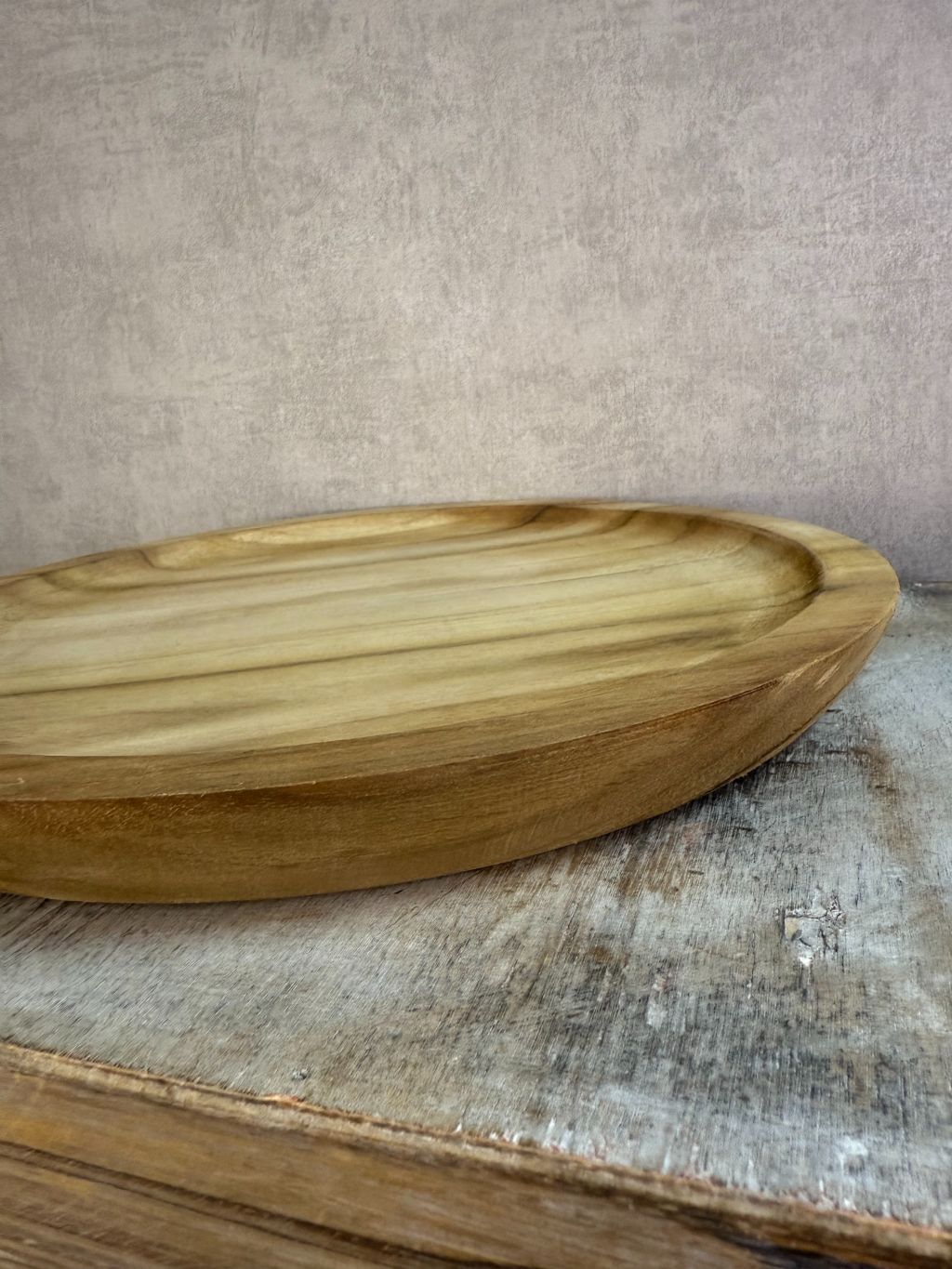 Dienblad Teak – rond houten dienblad van teakhout met natuurlijke nerven op een rustieke ondergrond.
