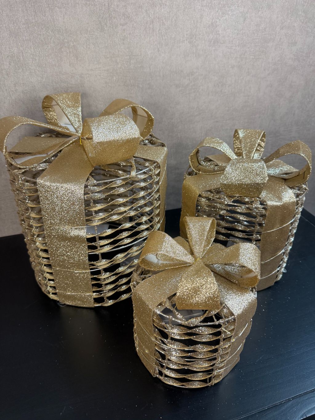 Set van 3 gouden kerstcadeau dozen met LED-verlichting en glinsterende strikken, in drie formaten.