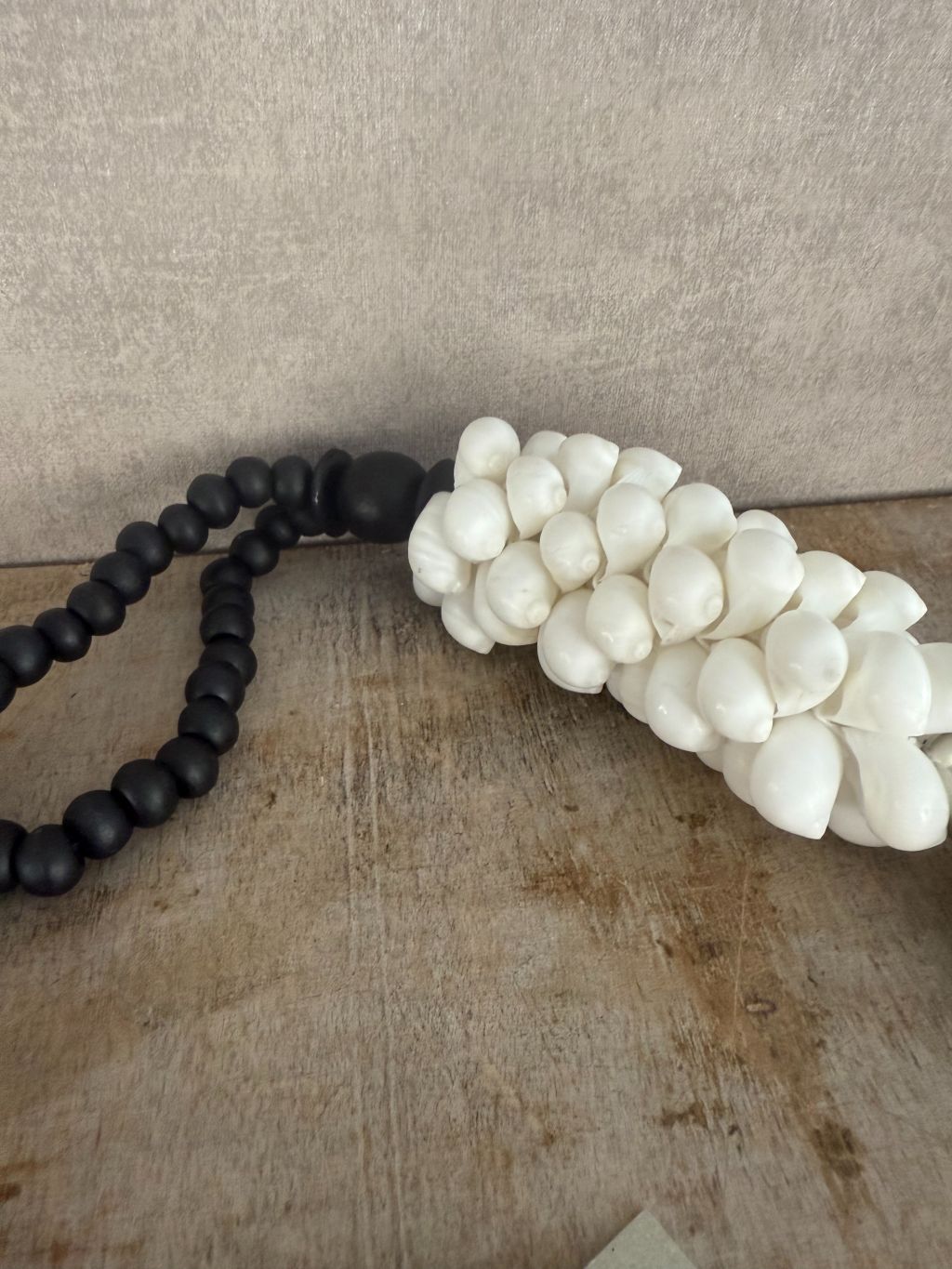 Zwart-witte decoratieve ketting met houten kralen, witte schelpen en zwarte kwast, handgemaakt.