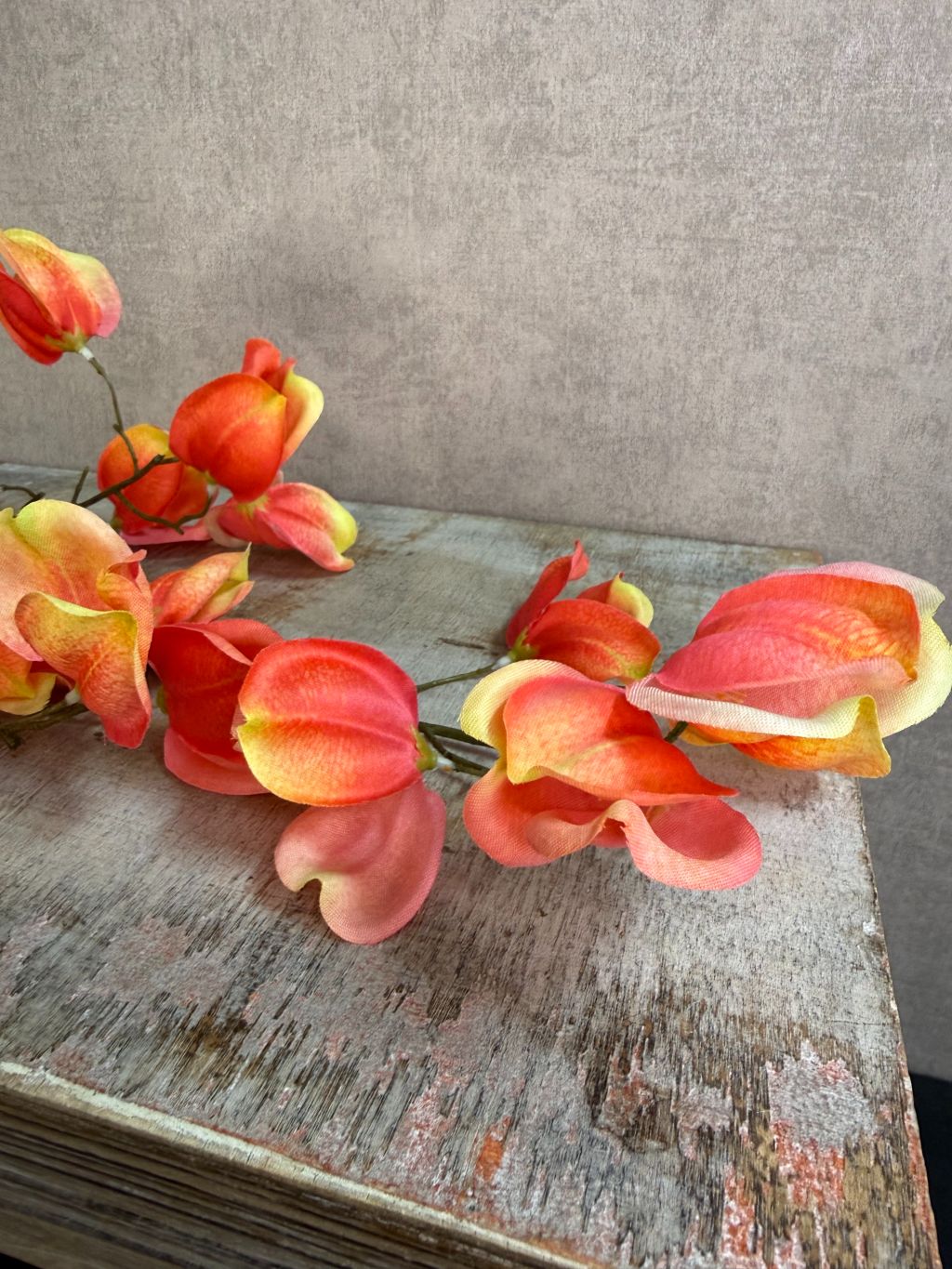 Kunstbloem Dipteronia met zalm-, oranje- en gele bloemblaadjes aan een lange groene steel tegen een neutrale achtergrond.