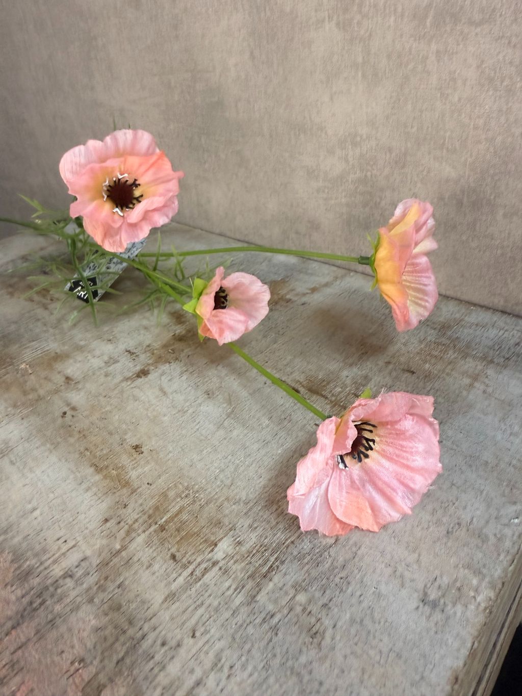 Roze kunstbloem klaproos met meerdere bloemknoppen op lange steel tegen een neutrale achtergrond.