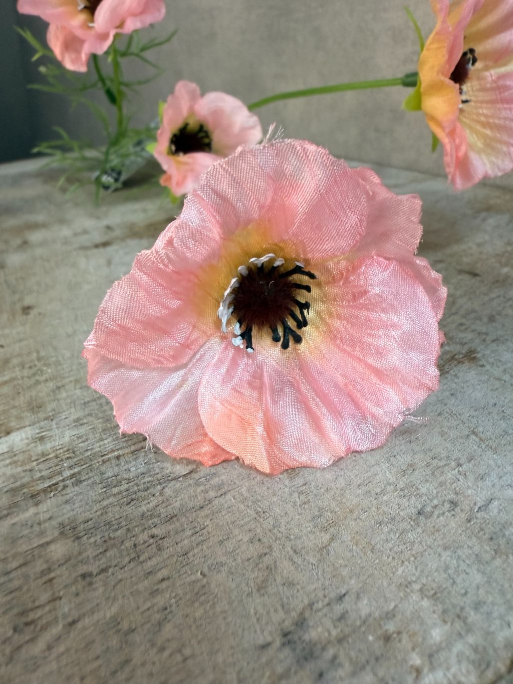 Roze kunstbloem klaproos met meerdere bloemknoppen op lange steel tegen een neutrale achtergrond.