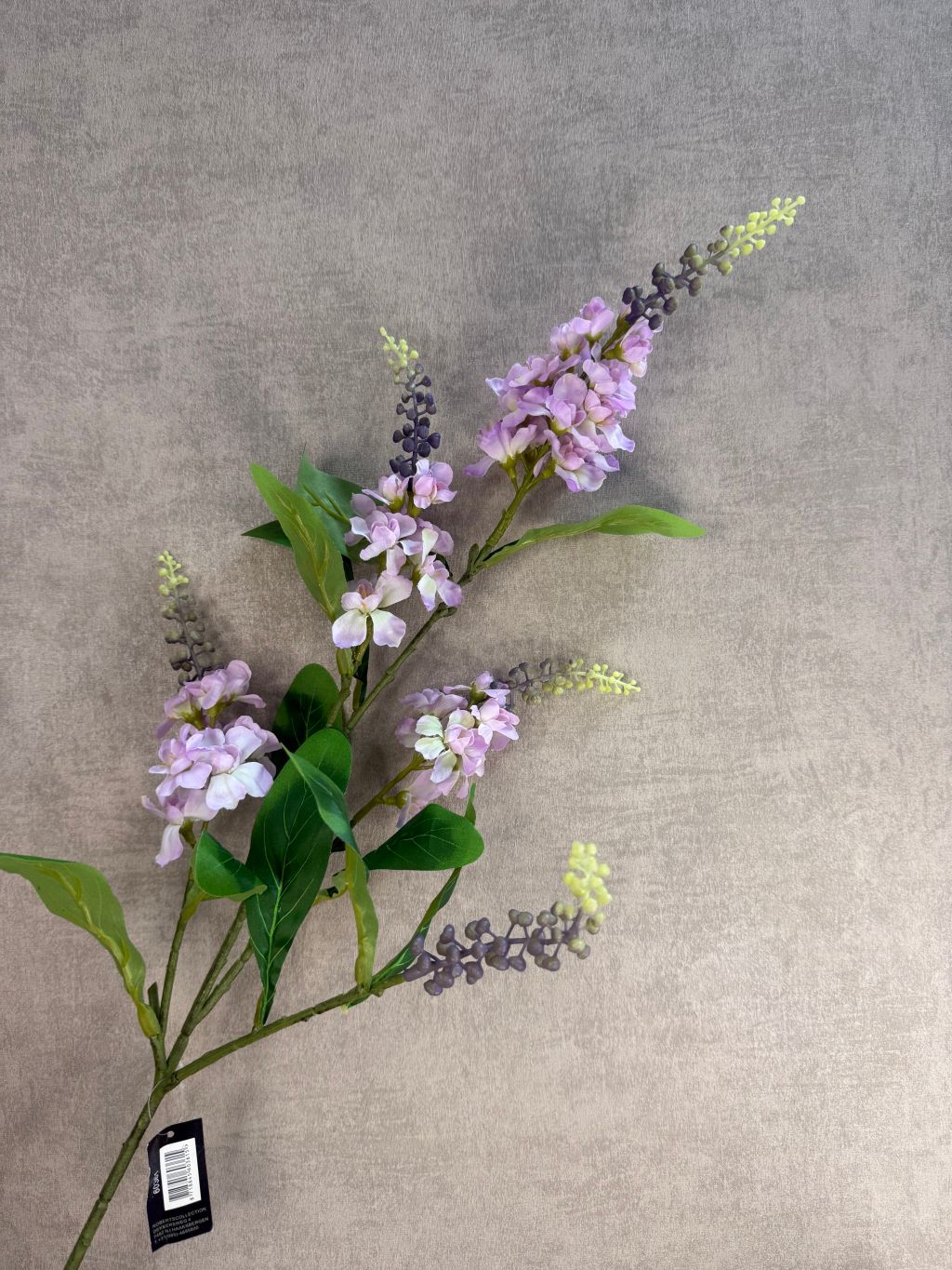 Kunstbloem lupine in lila tint met lange groene steel en bladeren, gefotografeerd tegen een zachte beige achtergrond.