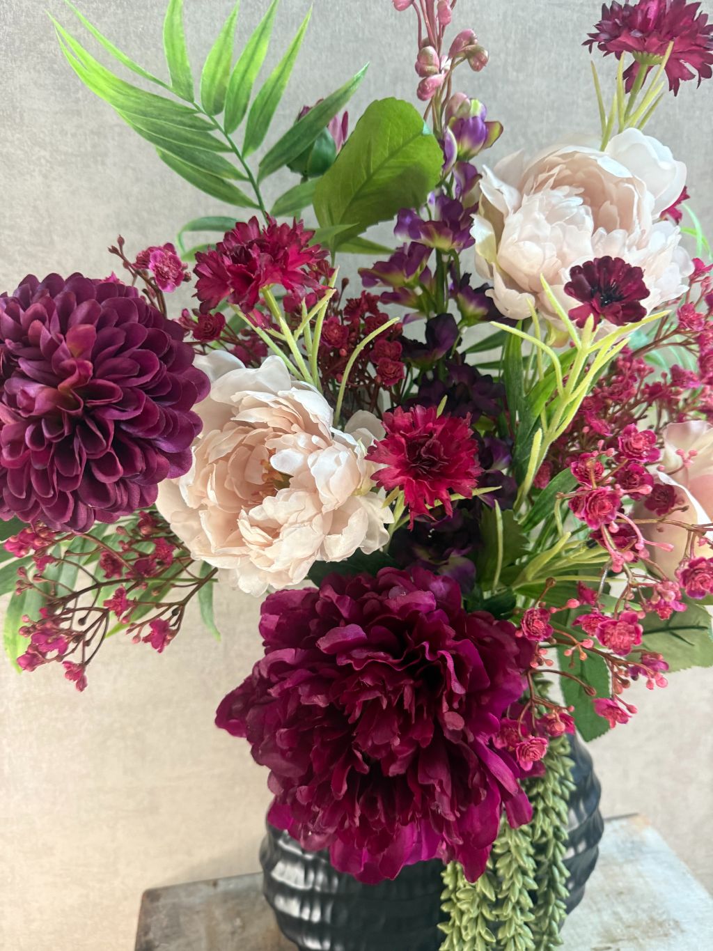 Kunstboeket Beau met bordeaux en roze bloemen, hangplant en groene accenten, front facing geschikt.