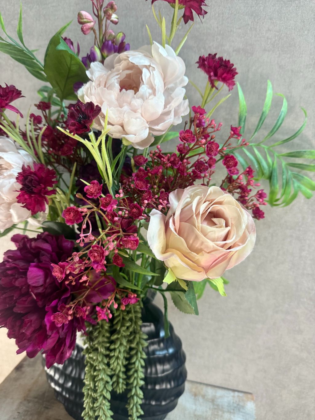 Kunstboeket Beau met bordeaux en roze bloemen, hangplant en groene accenten, front facing geschikt.