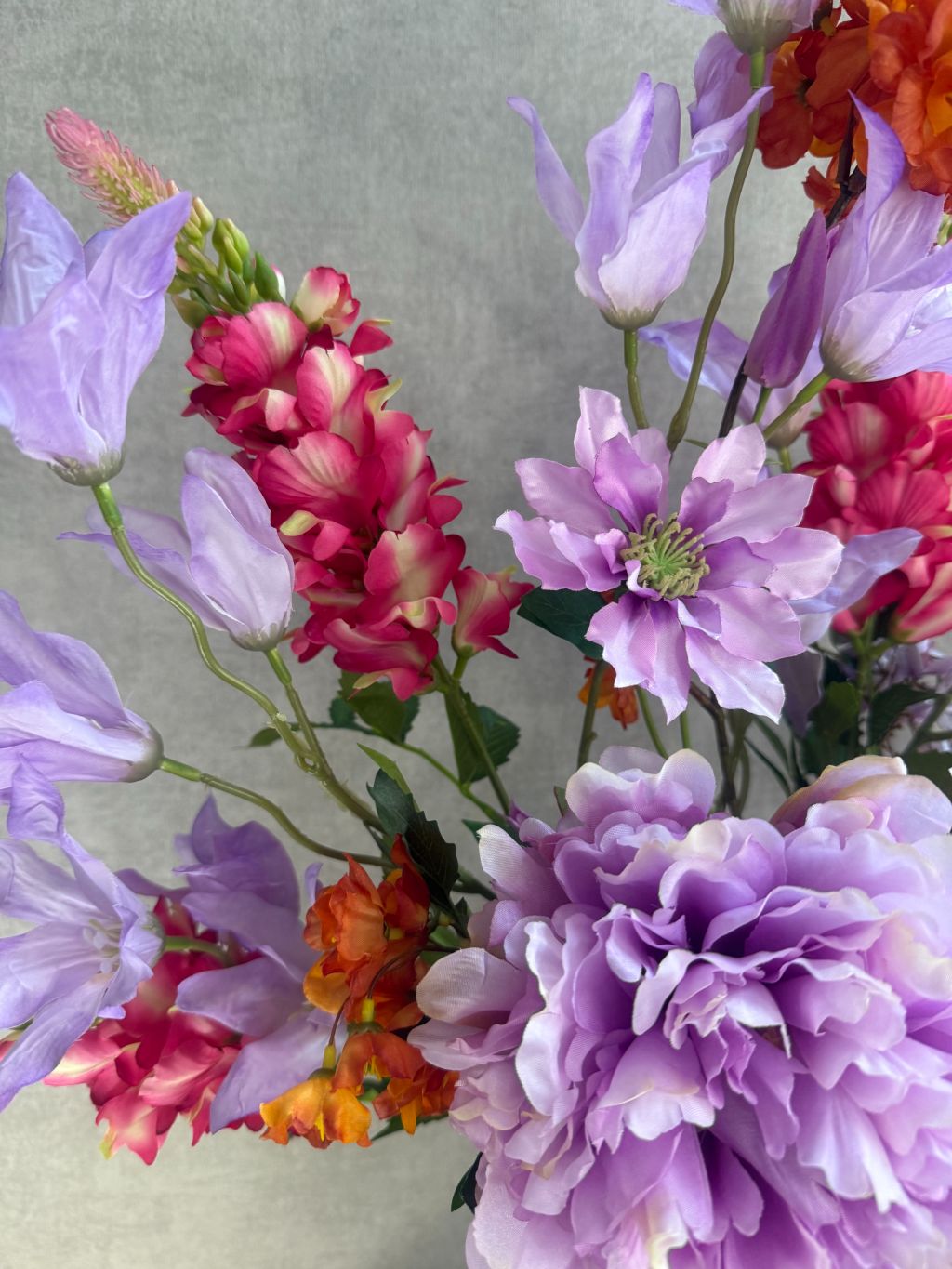 Kunstboeket met paarse, roze en oranje bloemen, front-facing geschikt voor vensterbank of wandmeubel.