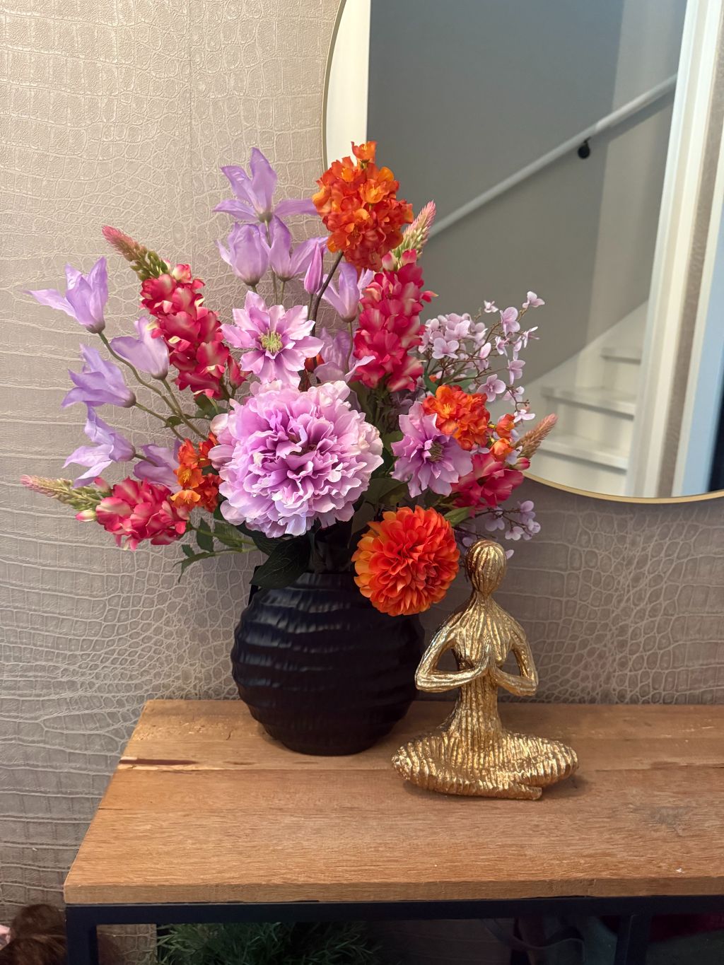 Kunstboeket La fleur op dressoir in zwarte vaas met gouden yoga beeld.