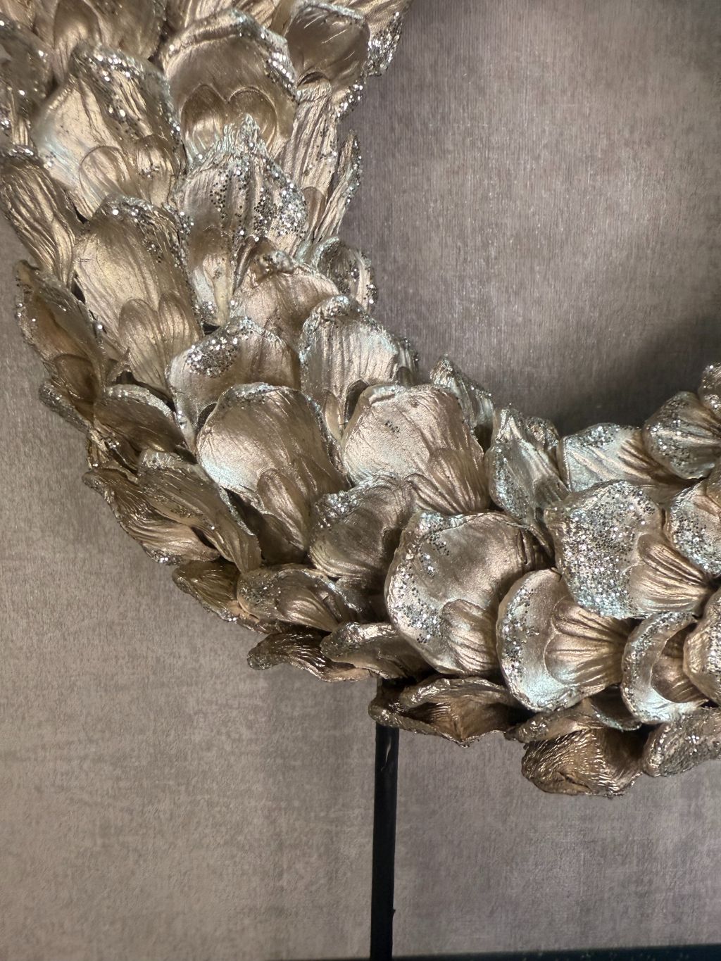 Ornament Krans glitter champagne – ronde decoratie met glanzende bladeren op zwarte standaard van Eglo Living.