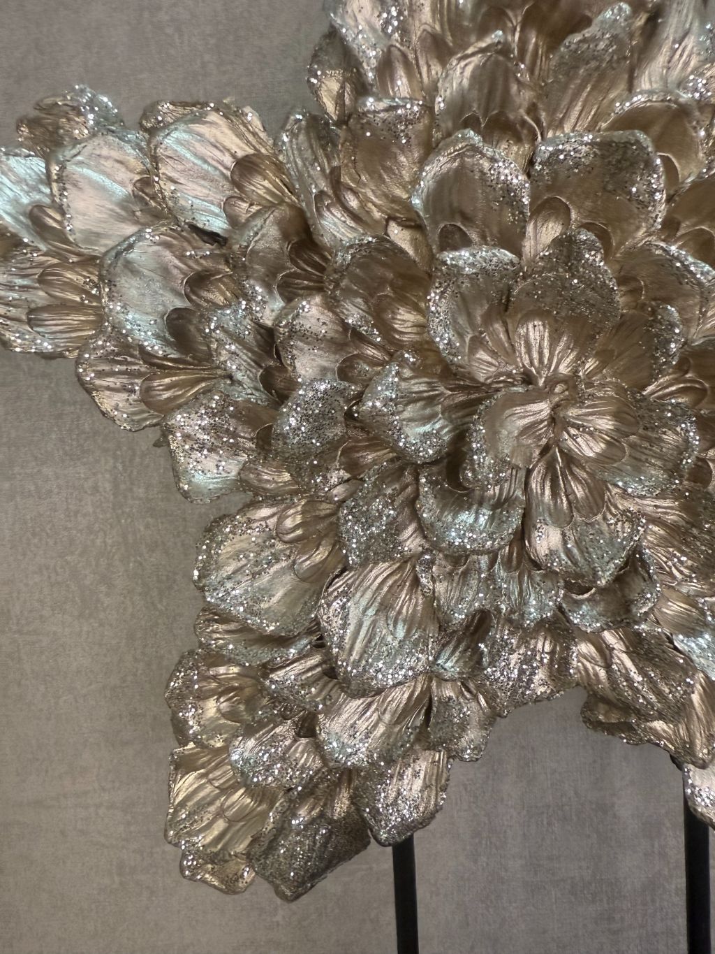 Ornament Ster glitter champagne – decoratieve ster met glanzende bloemvormige blaadjes op zwarte standaard.