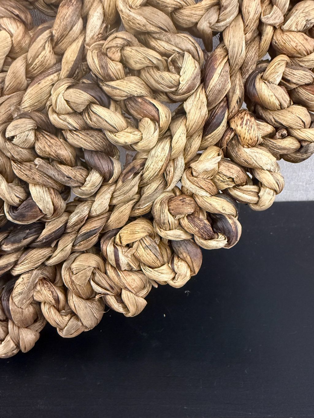 Ronde handgemaakte placemat van grof gevlochten raffia in warme bruintinten met decoratieve rand.