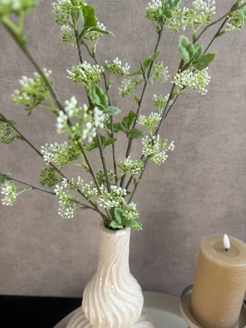 Decoratieset op beige dienblad met golvende vaas, kunsttakken, LED-kaarsen en amberblokjes in een houten schaaltje.