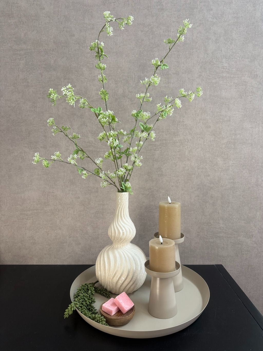 Decoratieset op beige dienblad met golvende vaas, kunsttakken, LED-kaarsen en amberblokjes in een houten schaaltje.