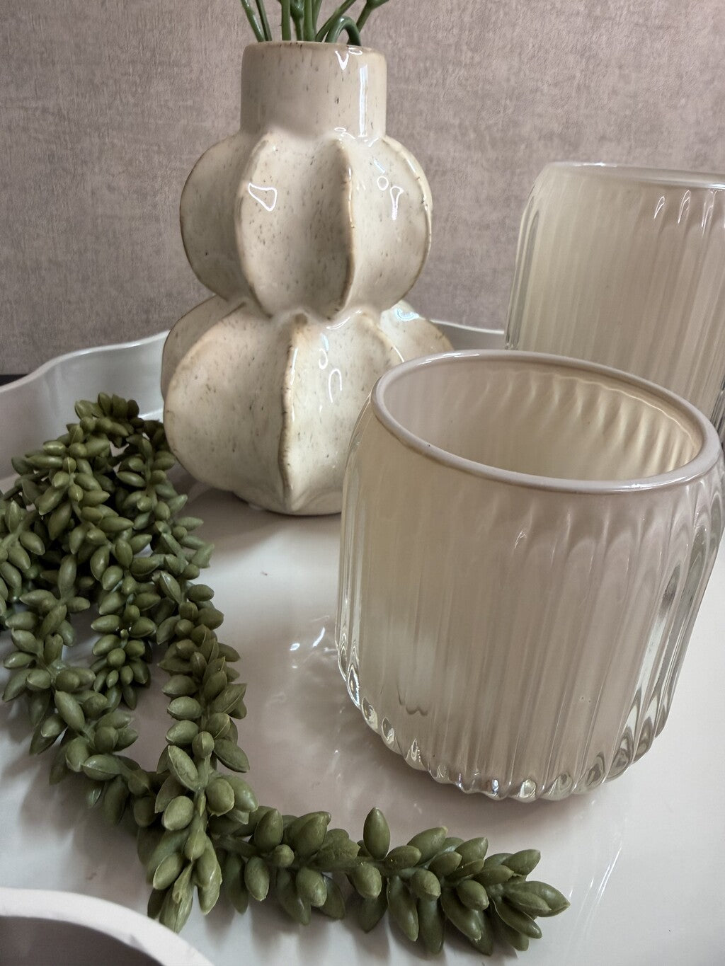 Tafel decoratie set Lulu met rond beige dienblad, vaas met roze bloemen, groene hangplant en twee glazen houders.