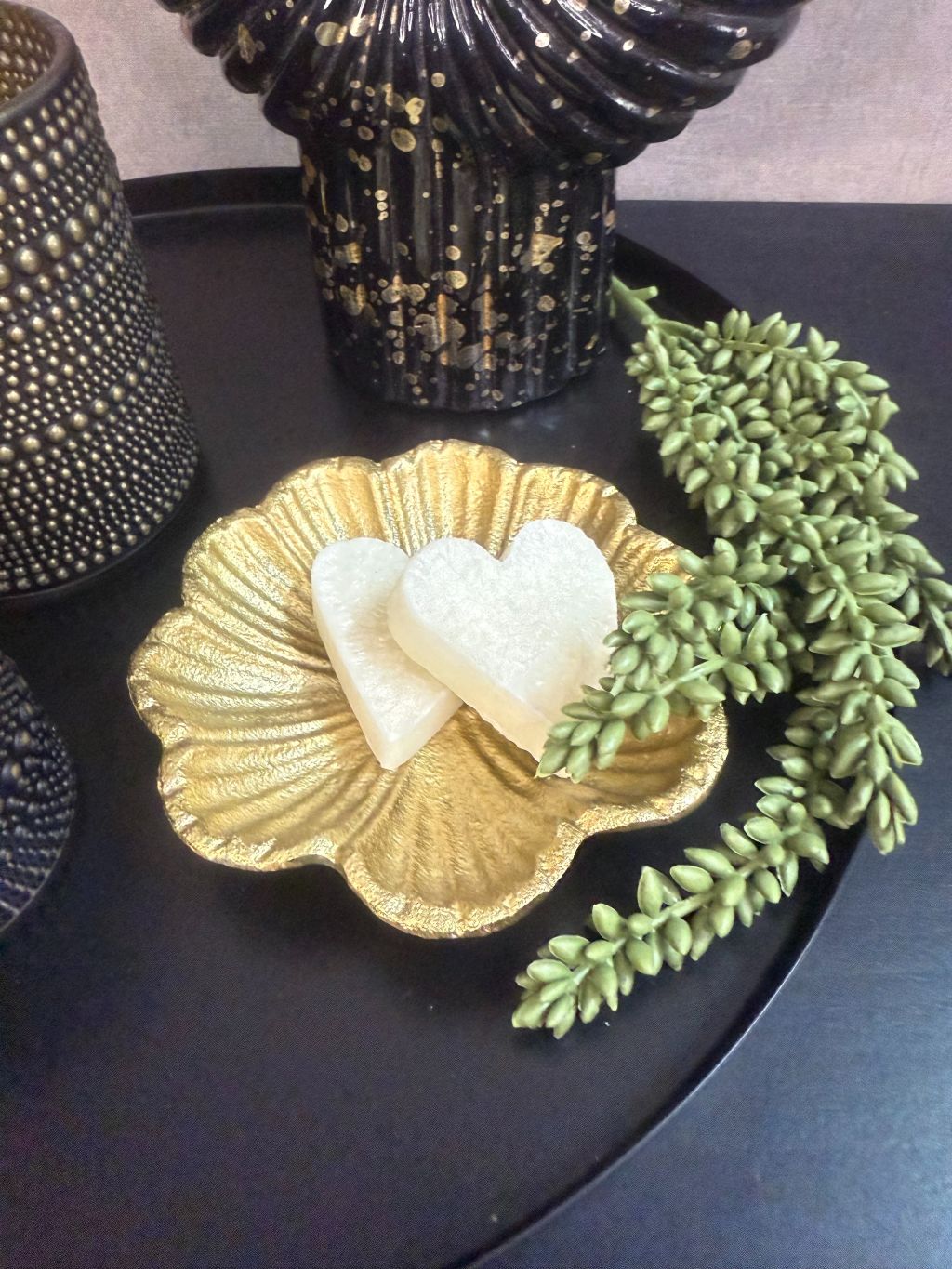 Tafel decoratie set Nelle – zwarte vaas met witte bloemen, goudkleurige schaal met amberblokjes en zwarte waxinelichthouders op rond dienblad.