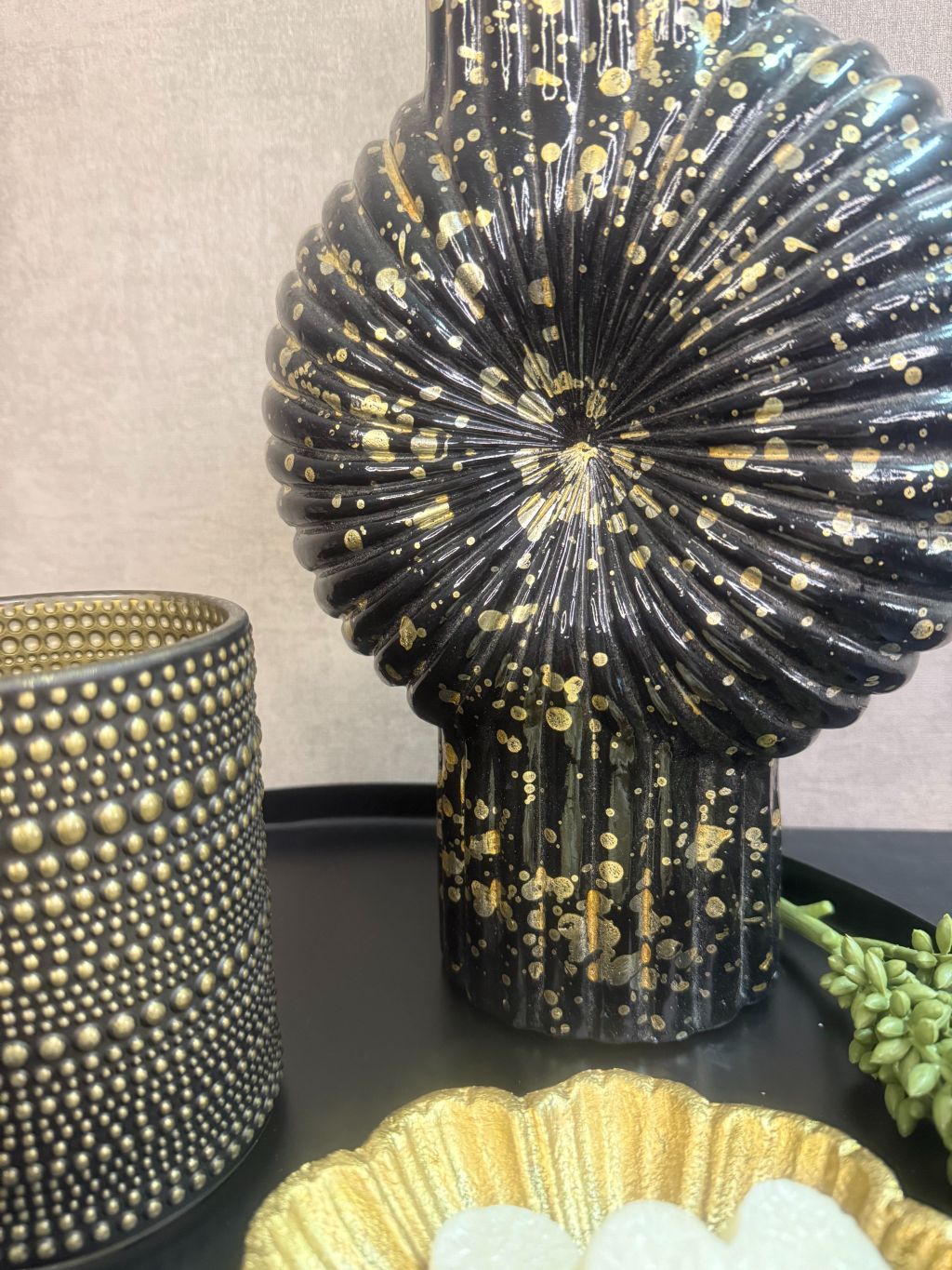 Tafel decoratie set Nelle – zwarte vaas met witte bloemen, goudkleurige schaal met amberblokjes en zwarte waxinelichthouders op rond dienblad.