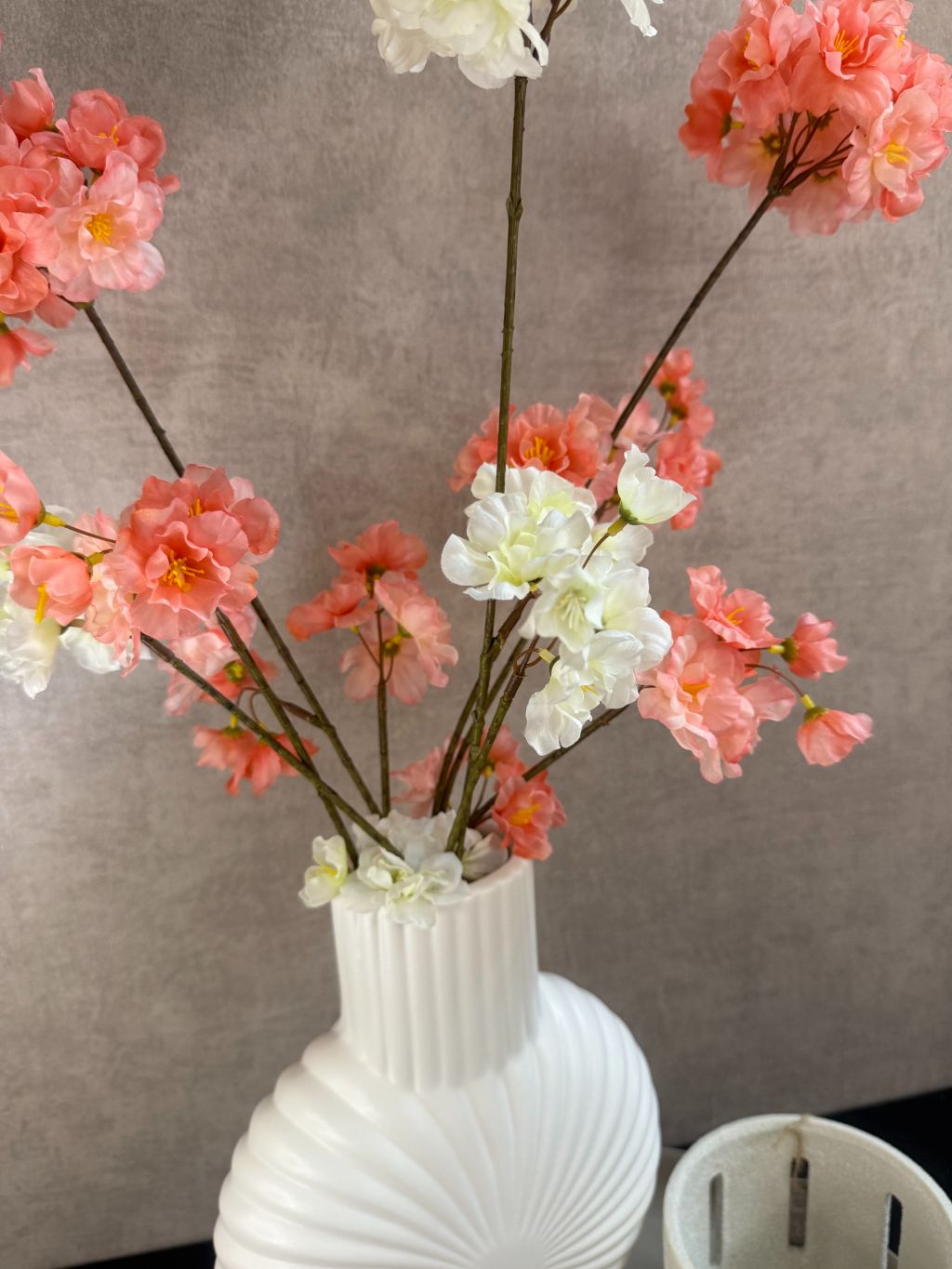 Tafeldecoratieset met witte vaas, zandkleurig dienblad, twee waxinelichthouders en kunsttakken met perzikroze en witte bloesems.