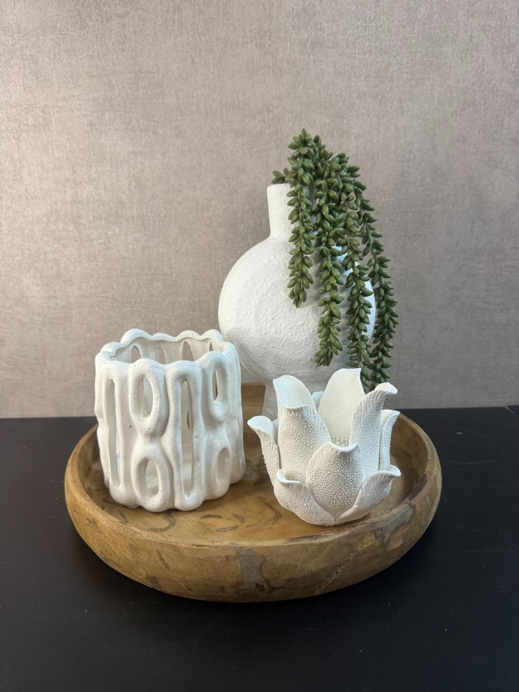 Tafel decoratie op houten schaal met wit keramiek: lotus theelichthouder, open waxinelichthouder en vaasje met hangende kunstplant.
