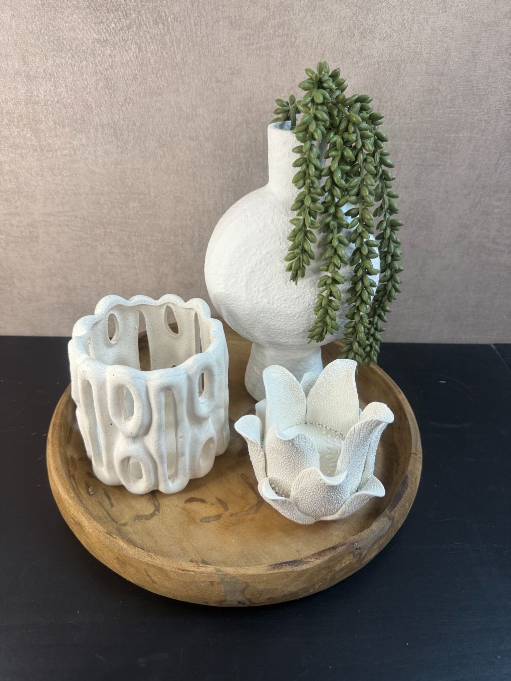 Tafel decoratie op houten schaal met wit keramiek: lotus theelichthouder, open waxinelichthouder en vaasje met hangende kunstplant.