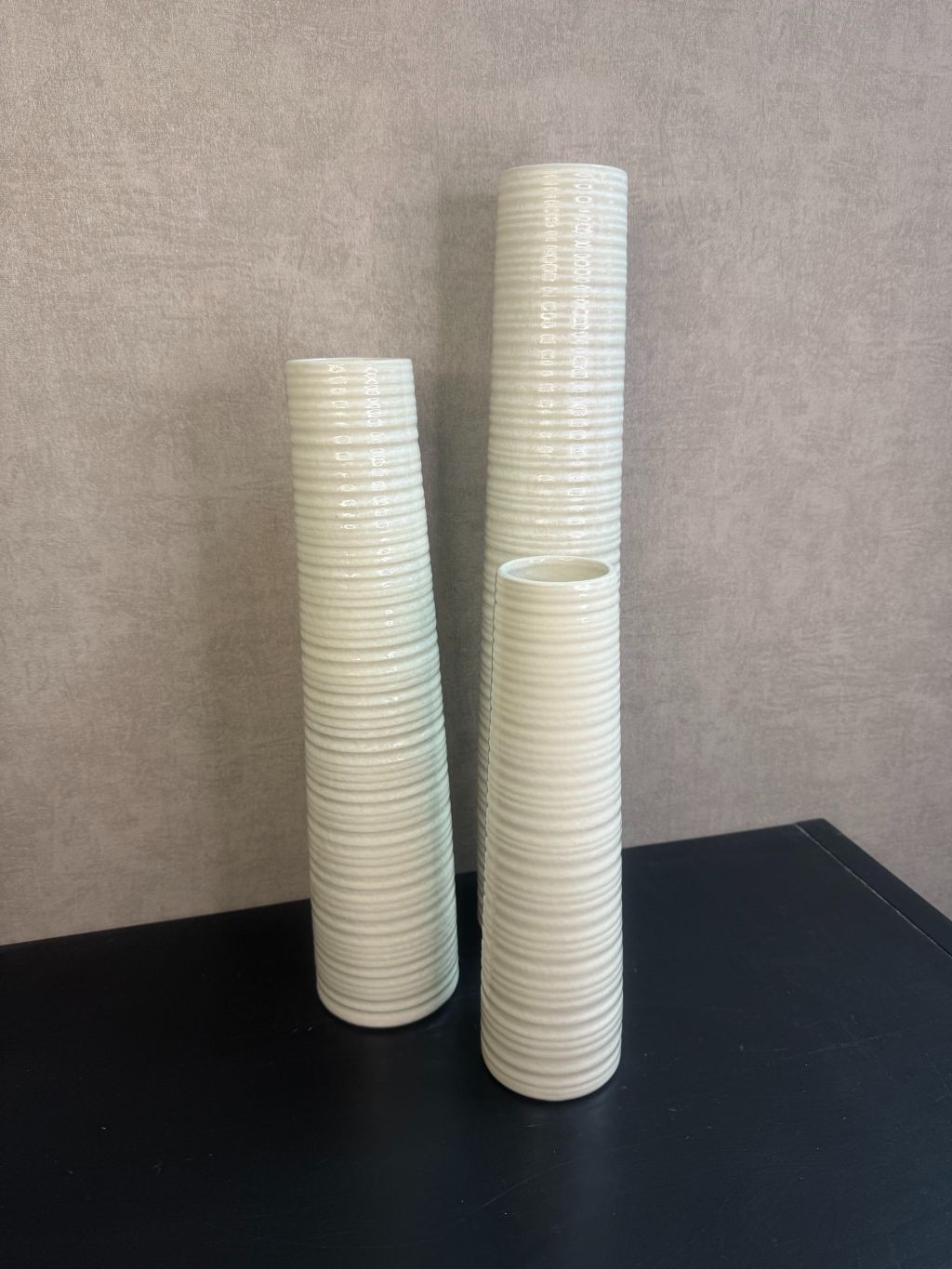 Vaas Gwinn crème – drie keramieken vazen met subtiele strepen in verschillende hoogtes tegen een grijze achtergrond.