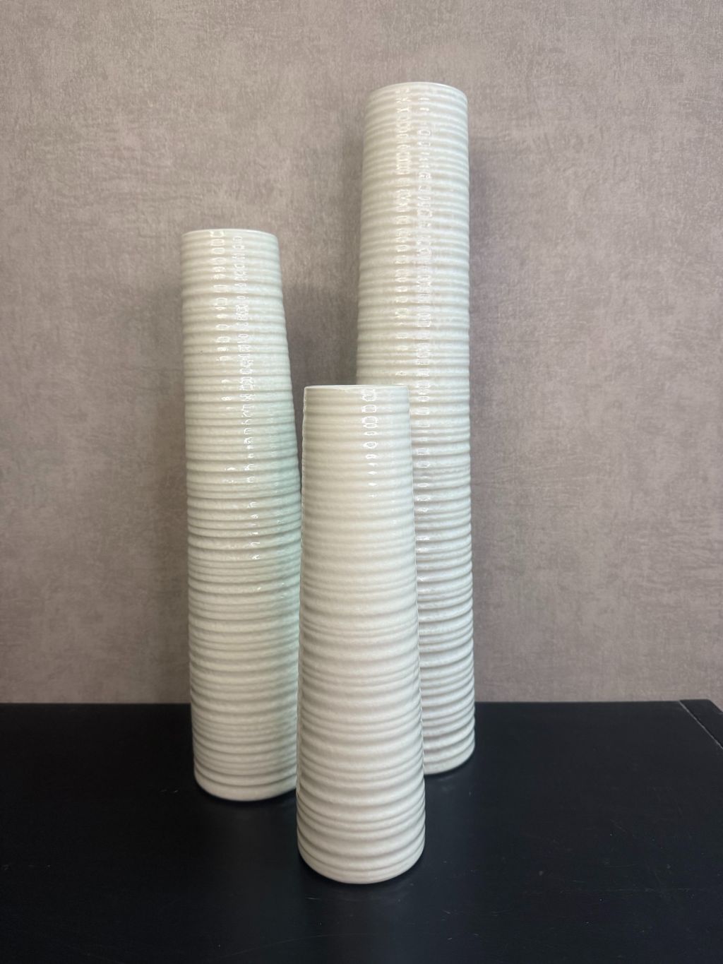 Vaas Gwinn crème – drie keramieken vazen met subtiele strepen in verschillende hoogtes tegen een grijze achtergrond.