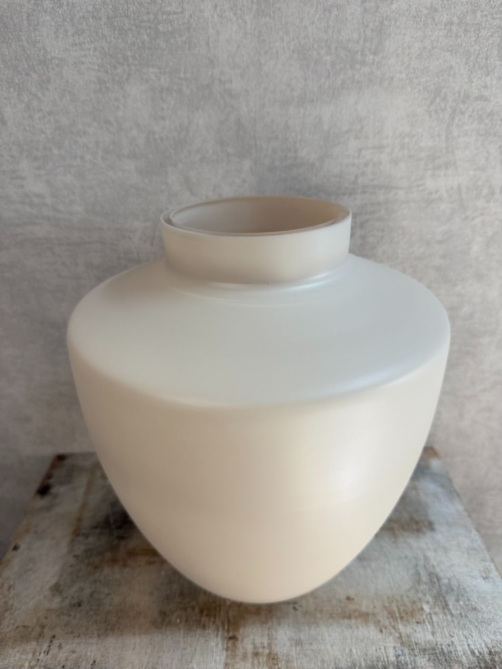 Vaas Tugela S in ivoorkleur met matte afwerking, staand op een houten ondergrond tegen een grijze wand.