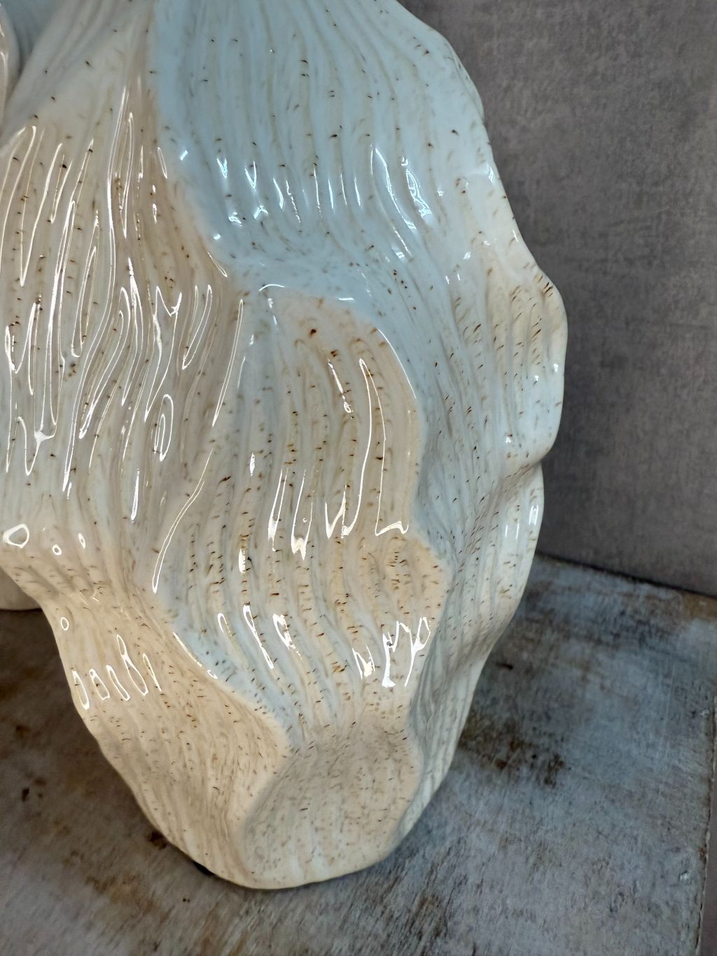 Beige keramieken vaas met golvend reliëfdesign van Homebound by Ky op een houten ondergrond.