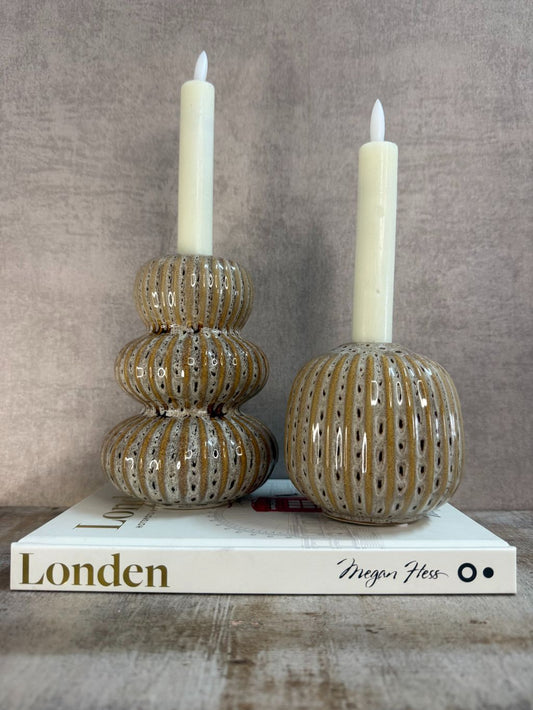 Vakkenkast decoratieset met twee beige keramieken kandelaars met LED-kaarsen en het witte tafelboek “Londen” van Megan Hess op houten ondergrond.