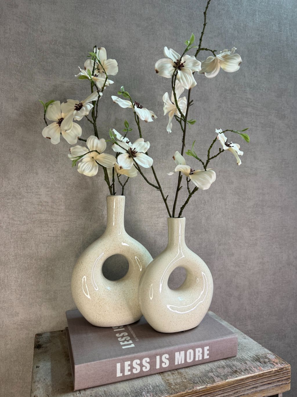 Vakkenkast decoratie set in taupe en beige met twee keramieken vazen, witte bloesemtakken en opbergboek Less is More.