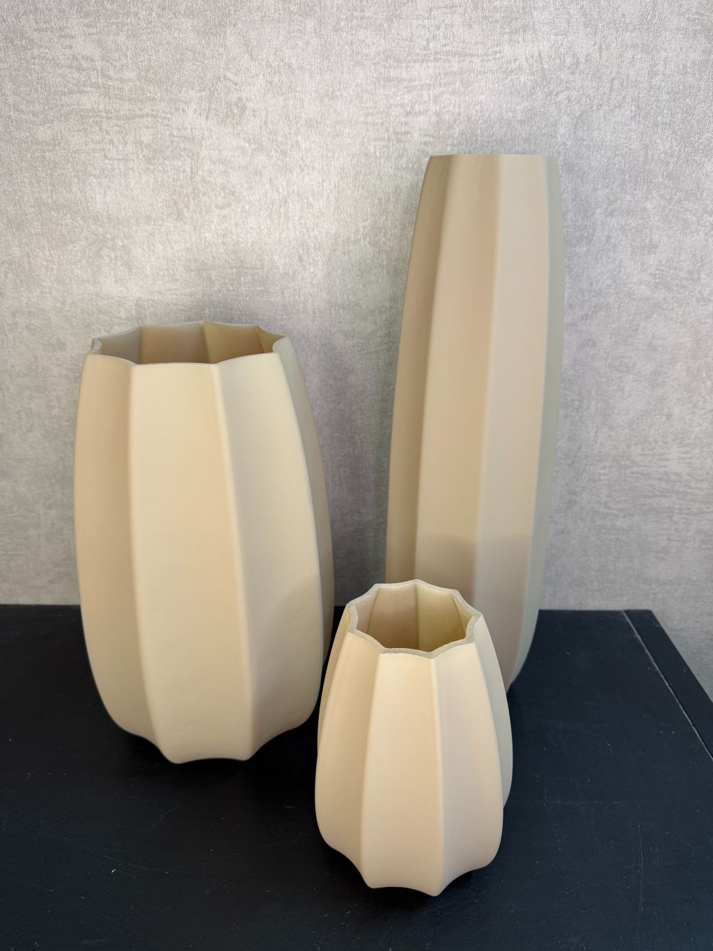 Bruine glazen vaas met facetvormig design in drie verschillende hoogtes, geplaatst op een donkere ondergrond.