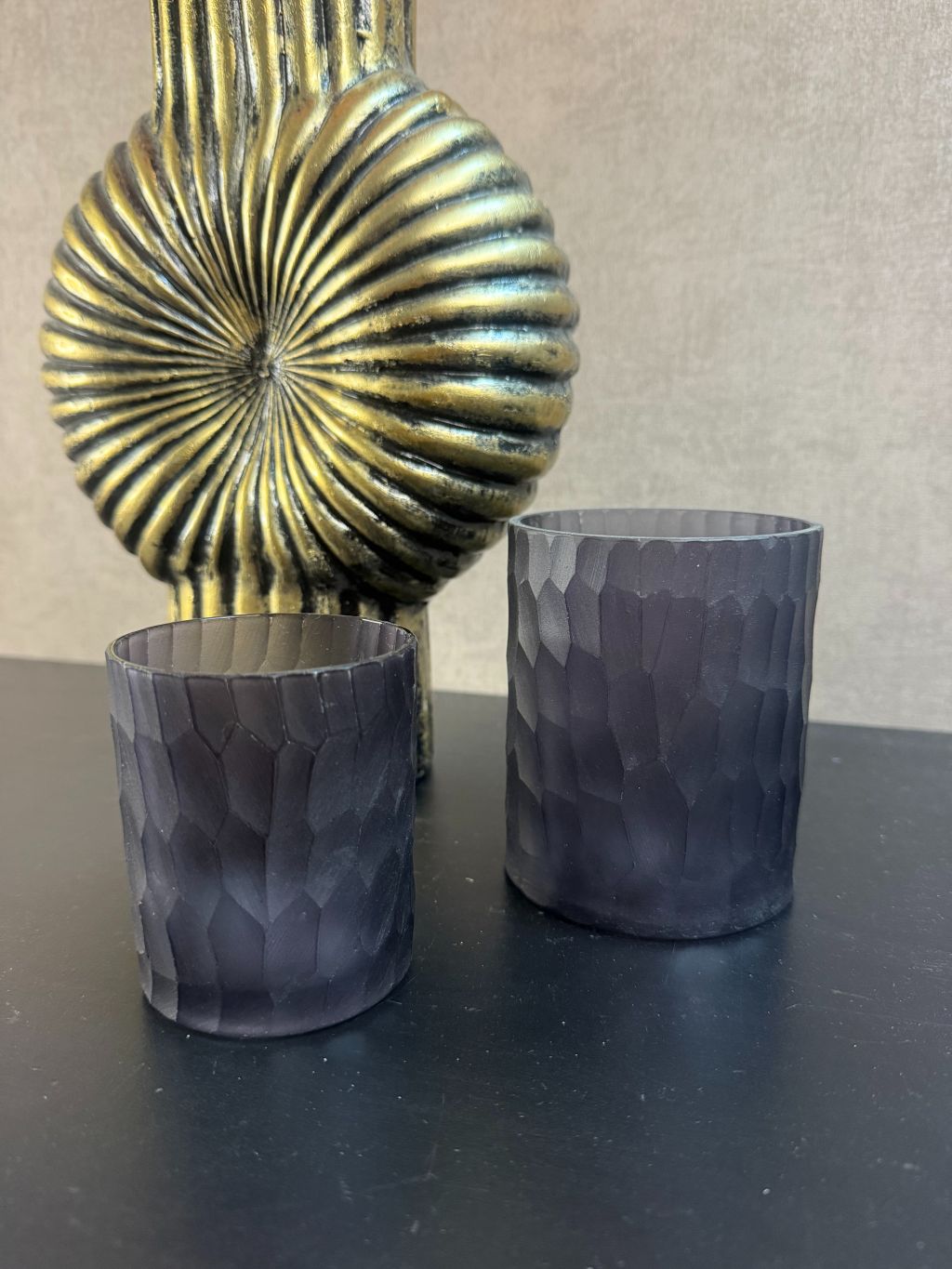 gouden ribbelvaas en twee zwarte waxinelichthouders.