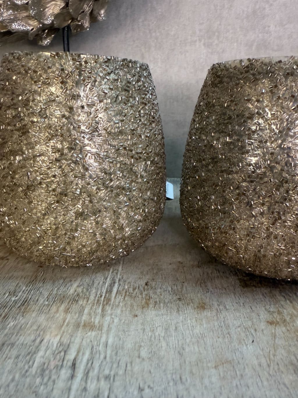 twee glinsterende waxinelichthouders op houten ondergrond.