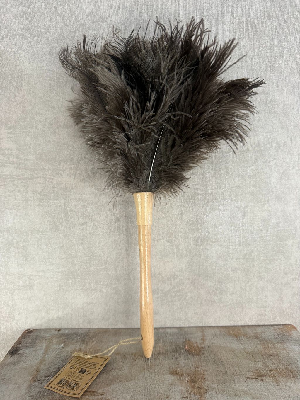 Veren plumeau met houten handgreep en bruine veren op houten ondergrond, geschikt voor het schoonmaken van delicate decoratie.
