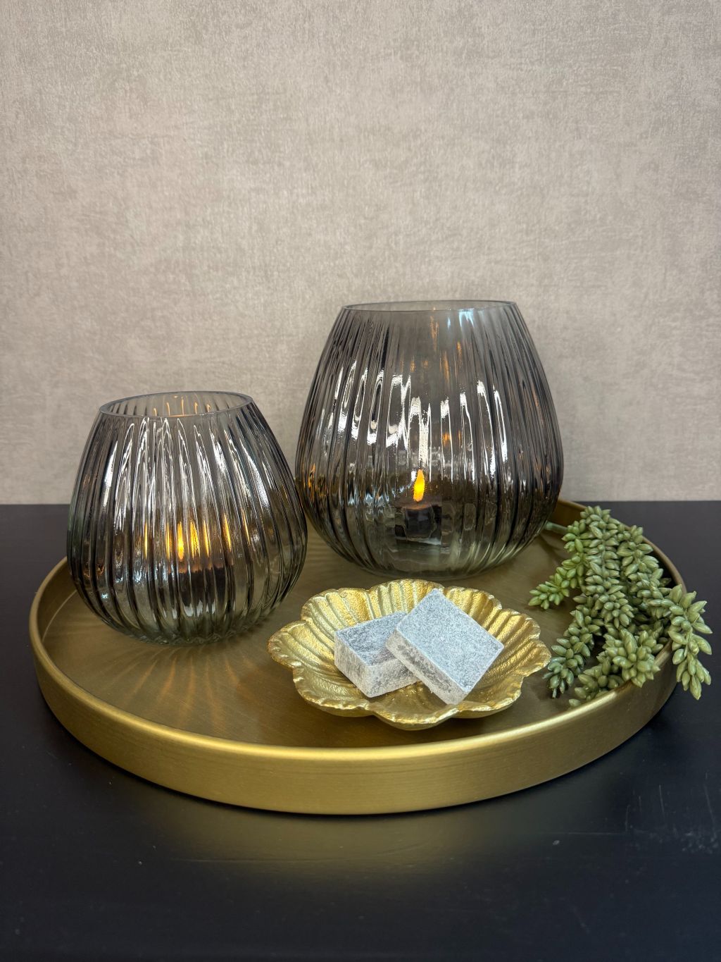 Tafel decoratie met een goud dienblad, waxinelichthouders en meer accessoires.