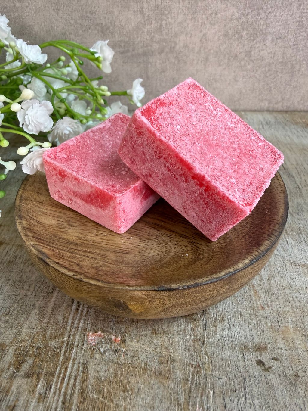 Roze amberblokjes met een frisse katoengeur op een houten schaaltje.