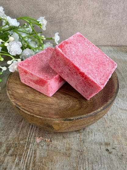 Roze amberblokjes met een frisse katoengeur op een houten schaaltje.