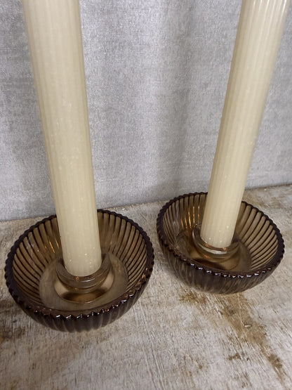 Cadeauset Lumière Amber van JENS Living met twee glazen kandelaars en twee beige dinerkaarsen.