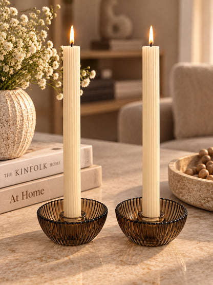 Cadeauset Lumière Amber van JENS Living met twee glazen kandelaars en twee beige dinerkaarsen.
