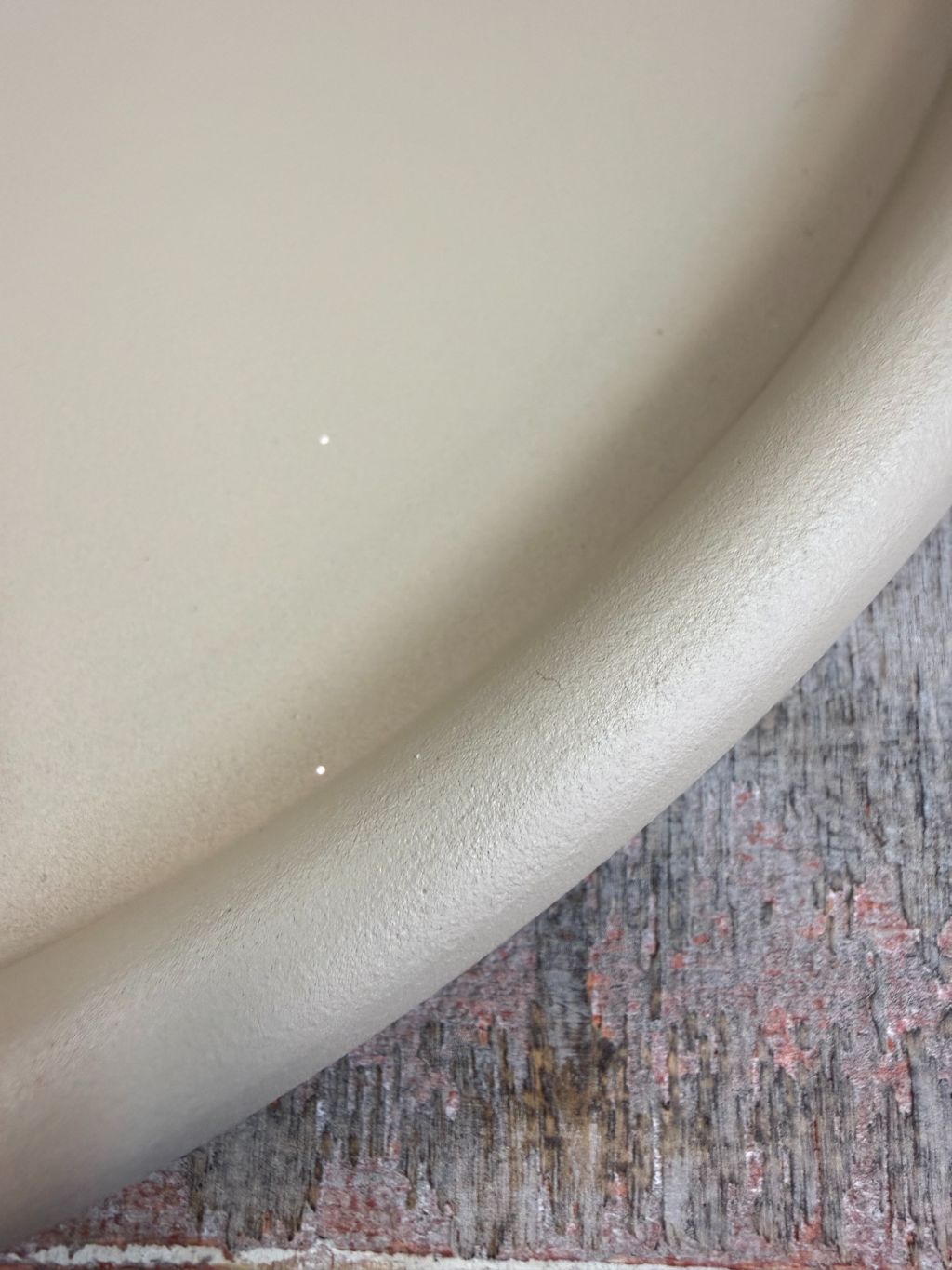 Rond beige metalen dienblad met matte afwerking, geplaatst op een houten ondergrond tegen een neutrale achtergrond.