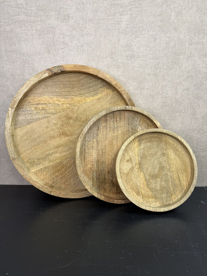 Drie ronde houten dienbladen in verschillende formaten met een natuurlijke houtnerf en opstaande rand.