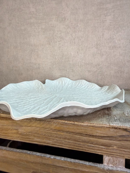 Crèmekleurig dienblad in bladvorm met subtiele reliëfstructuur op een houten ondergrond.