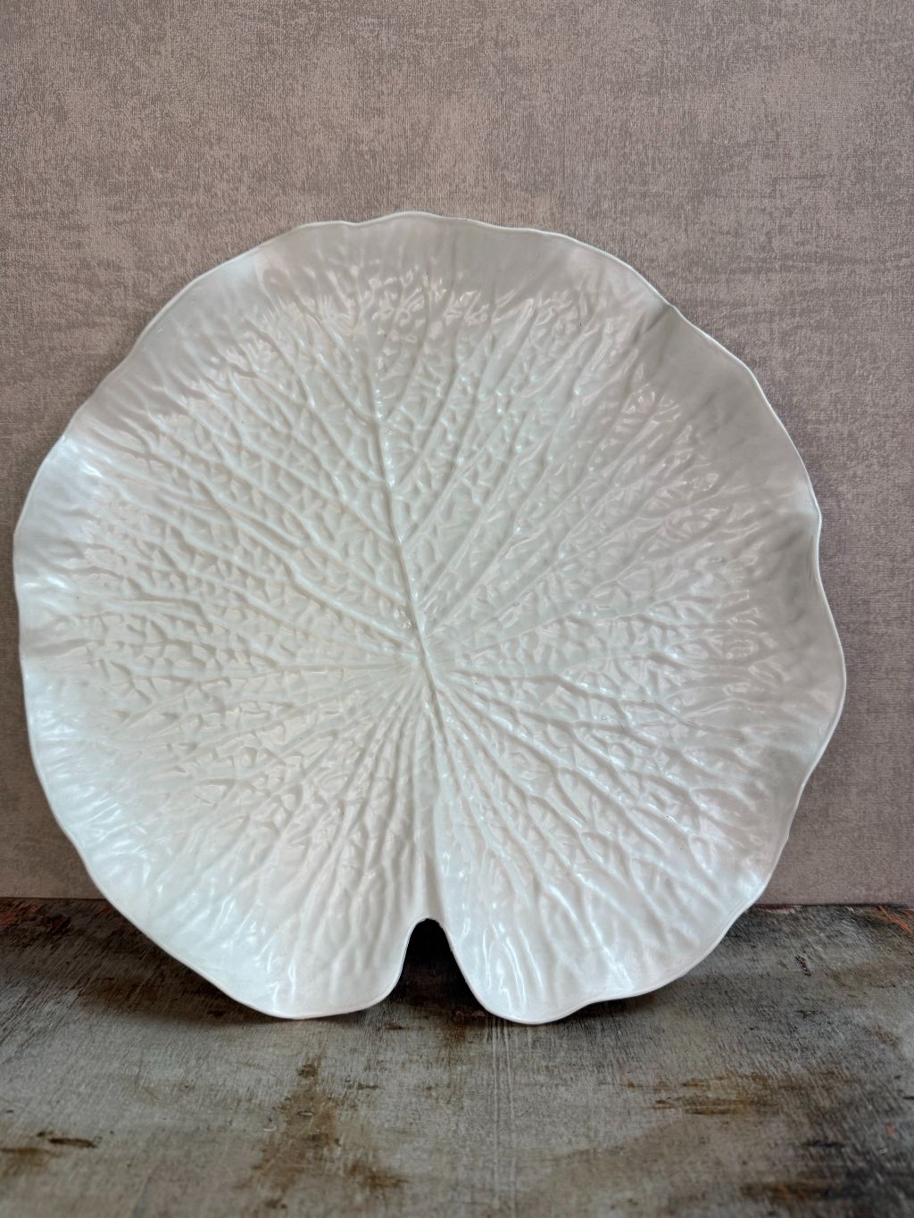 Crèmekleurig dienblad in bladvorm met subtiele reliëfstructuur op een houten ondergrond.