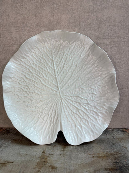 Crèmekleurig dienblad in bladvorm met subtiele reliëfstructuur op een houten ondergrond.