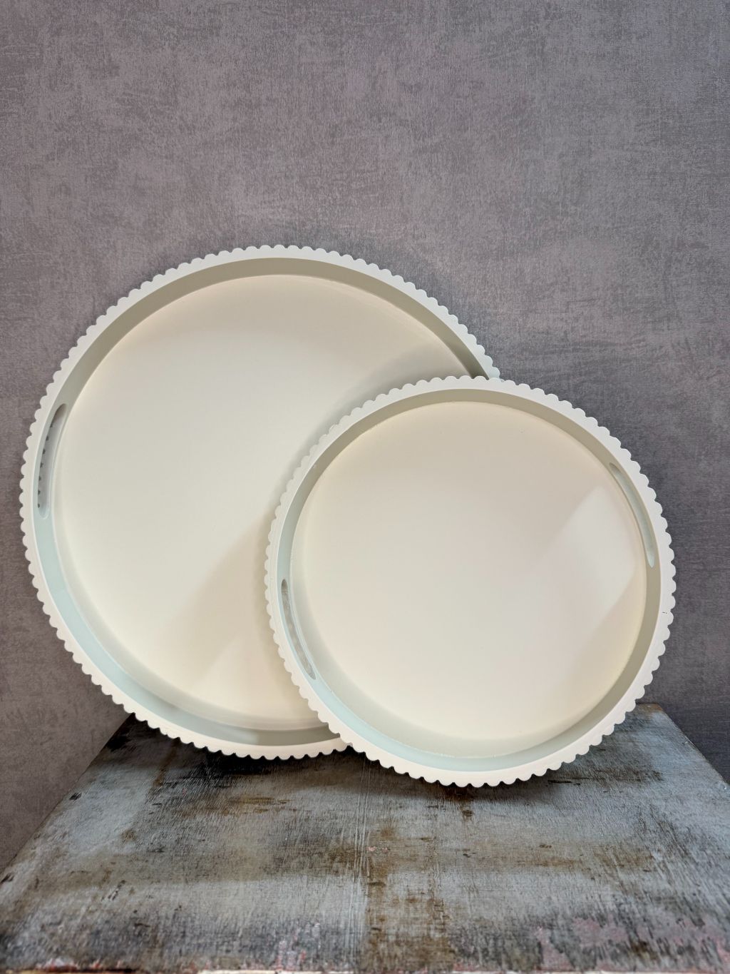 Twee beige houten dienbladen met geribbelde rand in klein en groot formaat, geplaatst tegen een neutrale achtergrond.