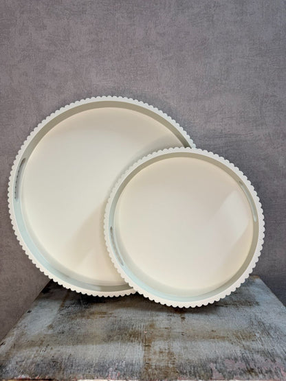 Twee beige houten dienbladen met geribbelde rand in klein en groot formaat, geplaatst tegen een neutrale achtergrond.