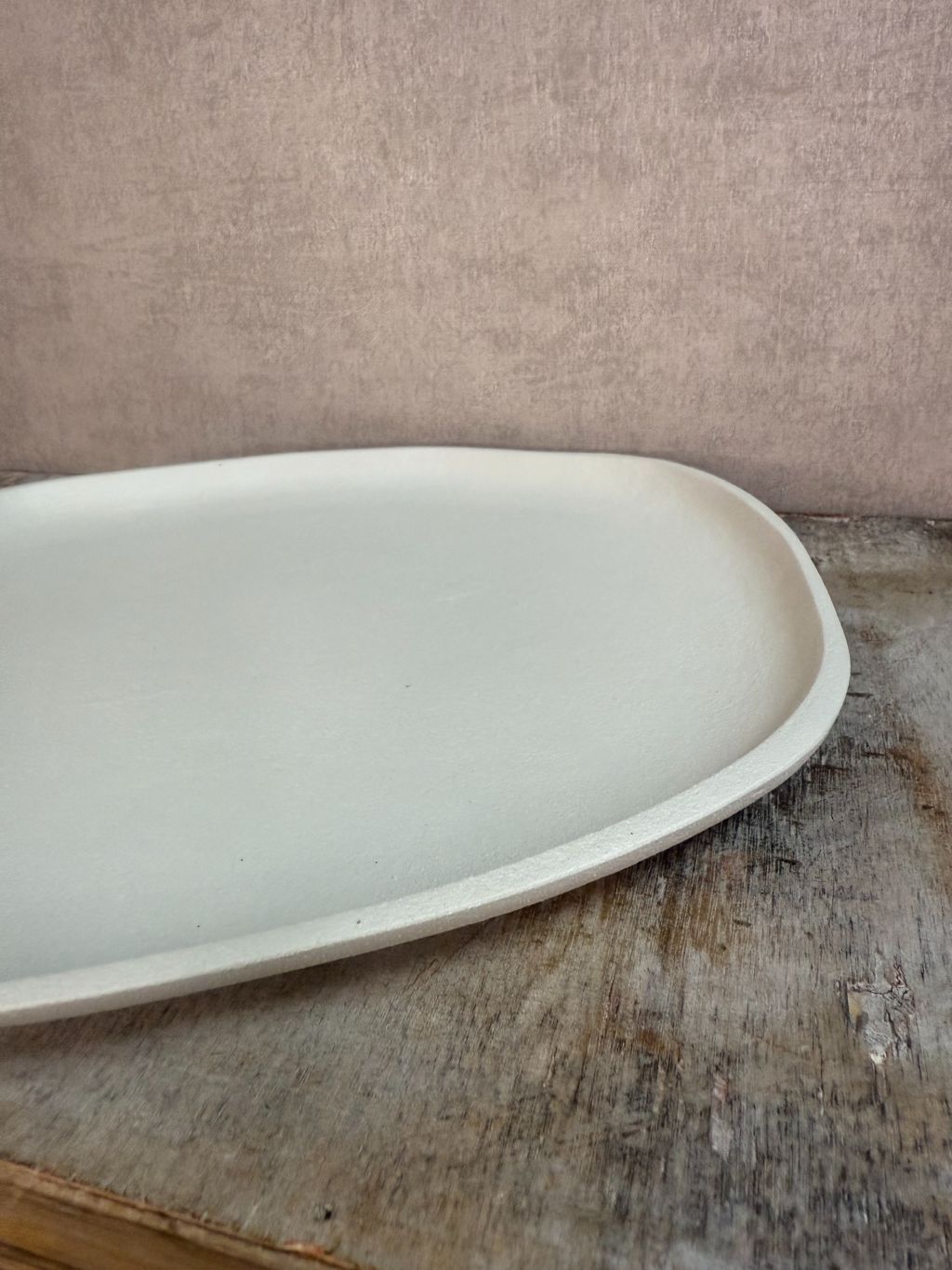 Dienblad Sandy in ivory kleur met organische vorm, gemaakt van duurzaam materiaal, op houten ondergrond tegen beige achtergrond.