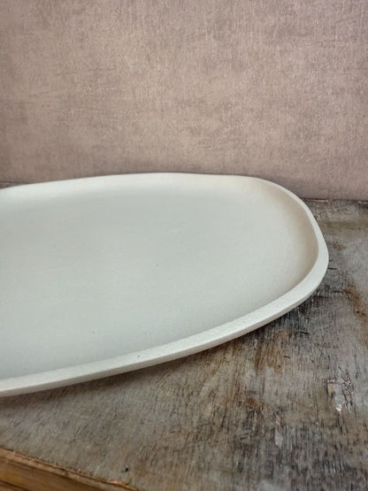 Dienblad Sandy in ivory kleur met organische vorm, gemaakt van duurzaam materiaal, op houten ondergrond tegen beige achtergrond.