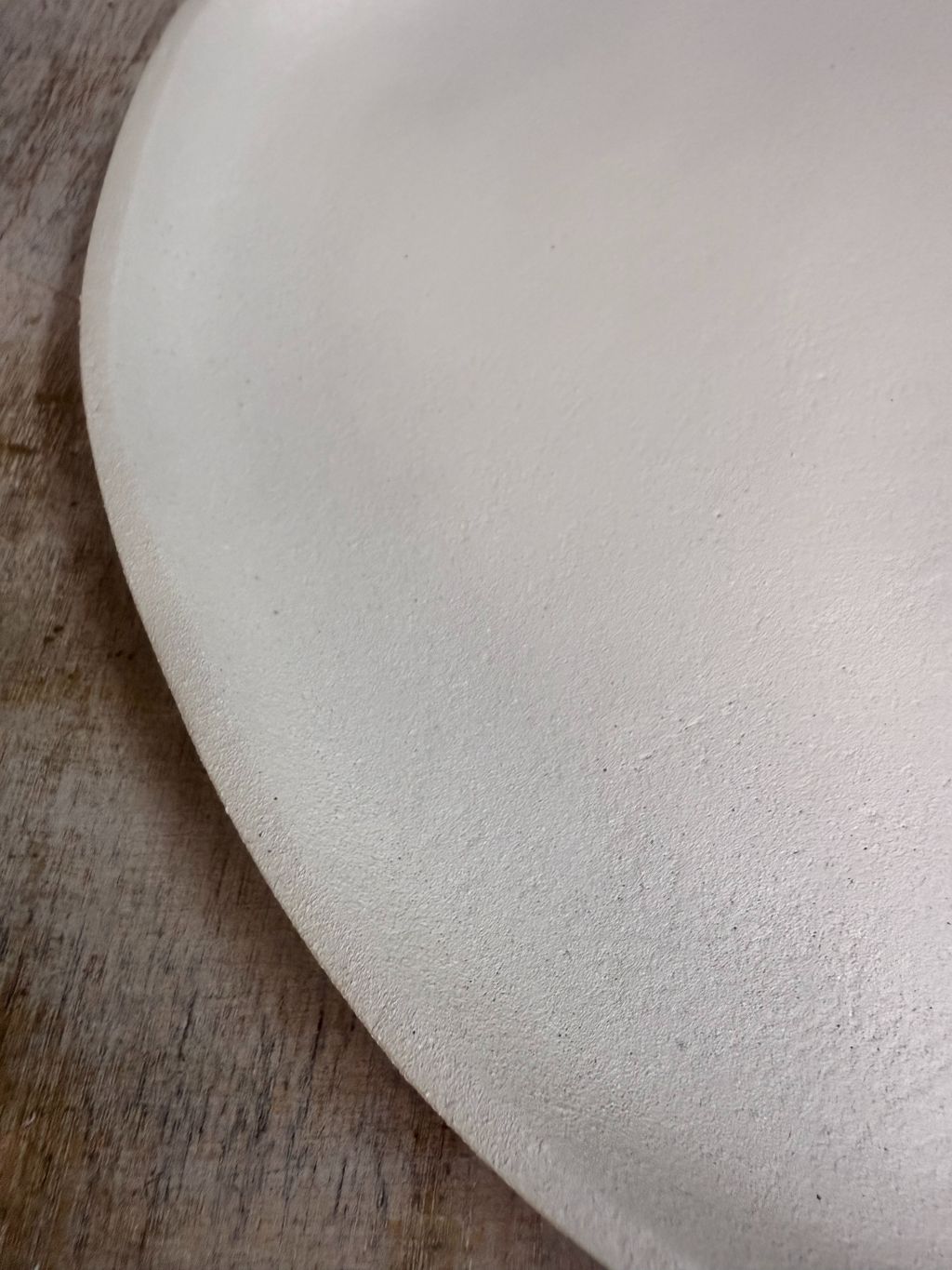 Dienblad Sandy in ivory kleur met organische vorm, gemaakt van duurzaam materiaal, op houten ondergrond tegen beige achtergrond.