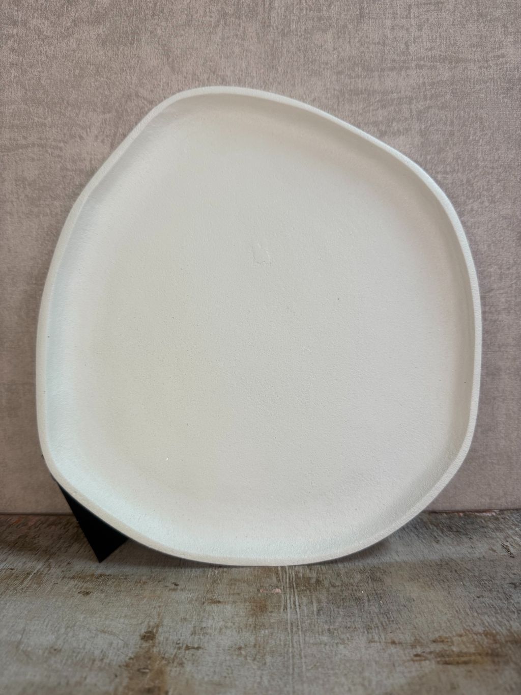 Dienblad Sandy in ivory kleur met organische vorm, gemaakt van duurzaam materiaal, op houten ondergrond tegen beige achtergrond.