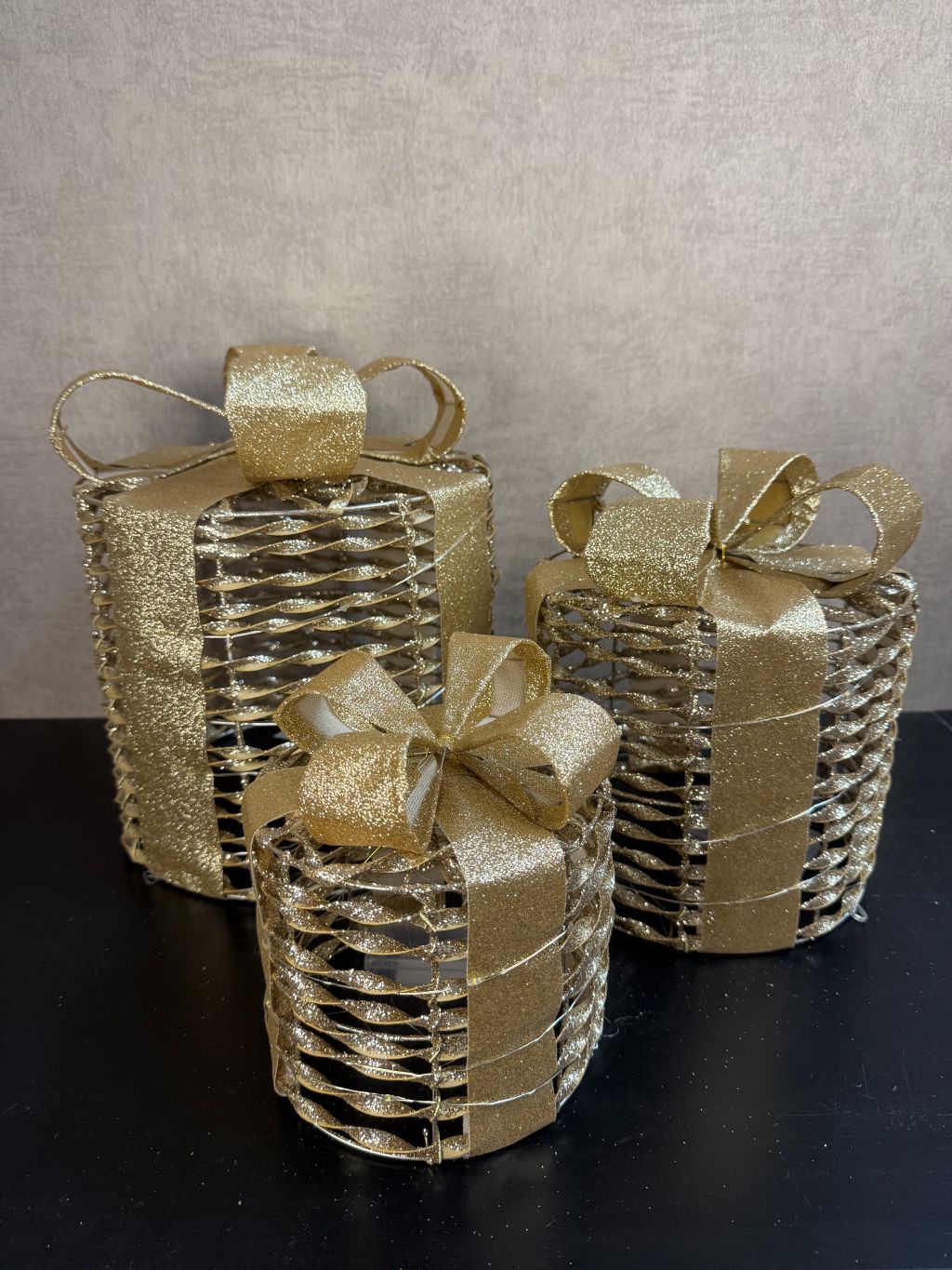 Set van 3 gouden kerstcadeau dozen met LED-verlichting en glinsterende strikken, in drie formaten.